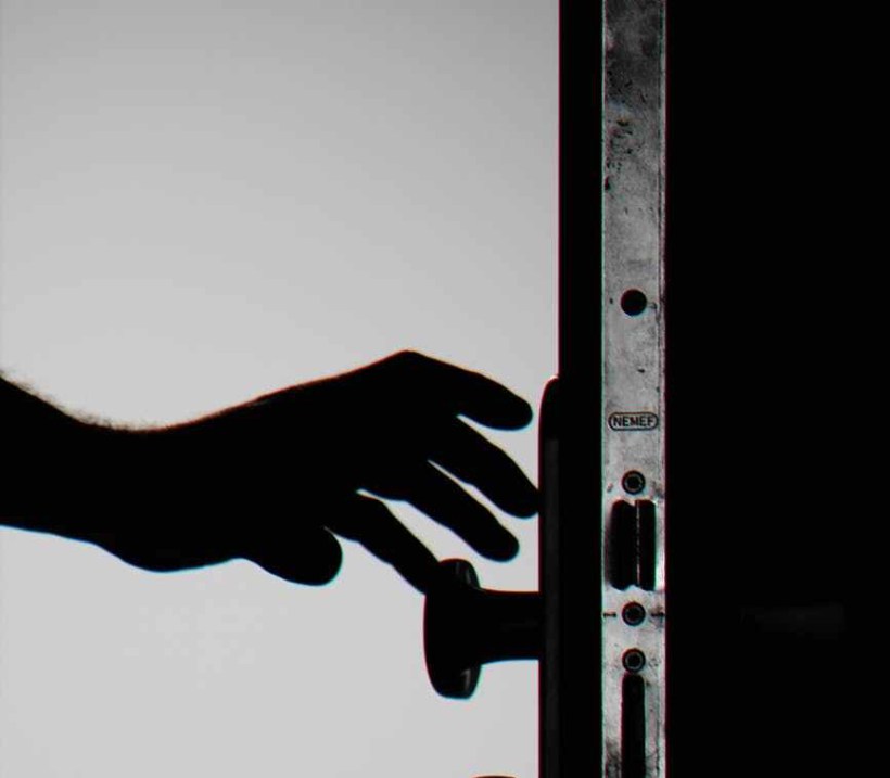 silhouette photo of person holding door knob